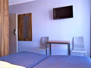 a bedroom with a bed and a table and a television at Hostel Annamarie in Szczecin
