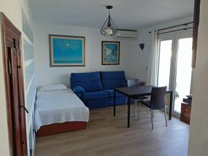 Una sala de estar con un sofá azul y una mesa. en Pura Vida, en Torremolinos