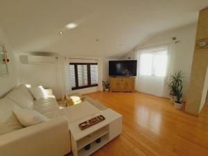 a living room with a white couch and a flat screen tv at Apartments Ana Žaborić, 70 m od šljunčane plaže in Zaboric