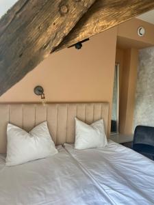 Bett mit weißen Kissen in einem Zimmer in der Unterkunft Rezidence Wannas Self Check in in Sigulda