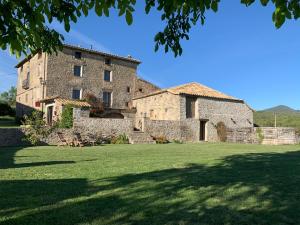 an old stone building with a grass field in front of it at Casa Lascorz in La Pardina