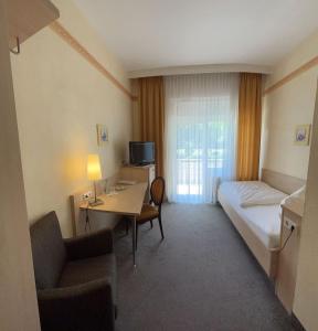 um quarto de hotel com um quarto com uma secretária e uma cama em Kurhotel Haus am Park em Erwitte