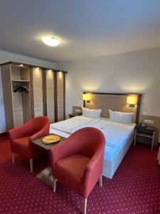 ein Hotelzimmer mit einem Bett und zwei Stühlen in der Unterkunft Kurhotel Haus am Park in Erwitte
