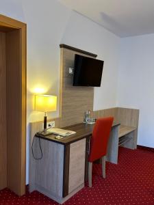 a room with a desk with a lamp and a television at Kurhotel Haus am Park in Erwitte