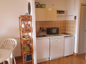 a small kitchen with a white refrigerator and a sink at Studio Le Lavandou, 1 pièce, 2 personnes - FR-1-308-183 in Le Lavandou