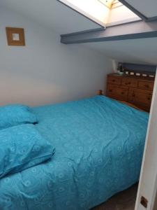 ein Schlafzimmer mit einem blauen Bett und einer Kommode in der Unterkunft Pavillon les pieds dans l'eau in Valras-Plage