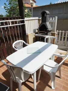 einen weißen Tisch und Stühle auf einer Terrasse mit Grill in der Unterkunft Pavillon les pieds dans l'eau in Valras-Plage