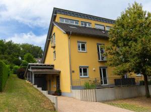 a yellow house with a black roof at Ferienhaus Moselhöhe - 2023 neu renoviert, mit Design-Ausstattung & großem Garten in Traben-Trarbach