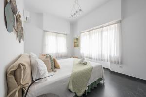 a white bedroom with a bed and two windows at Garden Villa Glyfada in Athens