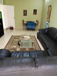 a living room with a leather couch and a table at Appartement 2 chambres Yoff Virage Dakar Senegal in Dakar