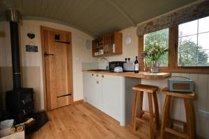 a kitchen with a stove and a counter with stools at The Shepherds Hut in Carmarthen