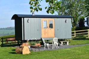a small shed with a table and chairs in a yard at The Shepherds Hut in Carmarthen