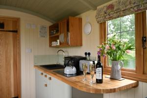 a kitchen with two glasses of wine and flowers on a counter at The Shepherds Hut in Carmarthen