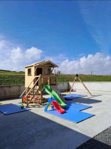 a playground with a slide and a play house at Àit Sèan Òg - 2bedroom self catering apartment 