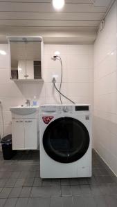 uma máquina de lavar roupa num quarto com um lavatório em Tunnelmallinen puutalohuoneisto. em Turku