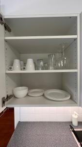 a shelf with plates and dishes in a kitchen at Tunnelmallinen puutalohuoneisto. in Turku