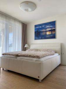 a white bed in a bedroom with a large window at See & You Familienwohnung mit Hotelanbindung in Pörtschach am Wörthersee