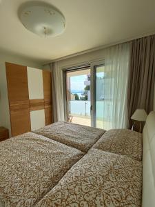a bedroom with a bed and a large window at See & You Familienwohnung mit Hotelanbindung in Pörtschach am Wörthersee
