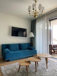 a blue couch in a living room with two tables at See & You Familienwohnung mit Hotelanbindung in Pörtschach am Wörthersee