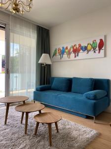 See & You Familienwohnung mit Hotelanbindung في بويرشاك آم فورثيرسي: غرفة معيشة مع أريكة زرقاء وطاولتين