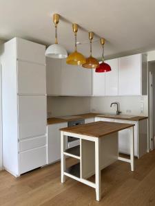 a kitchen with white cabinets and a wooden table at See & You Familienwohnung mit Hotelanbindung in Pörtschach am Wörthersee