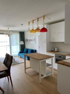See & You Familienwohnung mit Hotelanbindung في بويرشاك آم فورثيرسي: مطبخ وغرفة معيشة مع طاولة وأريكة زرقاء