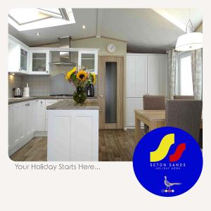 una cocina con armarios blancos y un jarrón de flores en un mostrador en Seton Sands Holiday Home en Port Seton