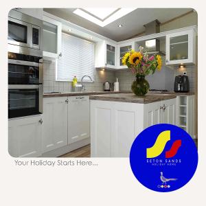 a kitchen with white cabinets and a vase of flowers at Seton Sands Holiday Home in Port Seton