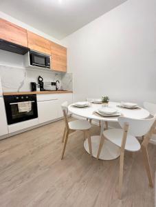 a white kitchen with a white table and chairs at Maison Coty - Hypercentre/Plage in Le Havre