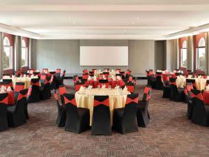 a conference room with tables and chairs and a screen at Ibis Melaka in Melaka