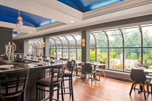 a restaurant with tables and chairs and large windows at Hampton Inn & Suites Stamford in Stamford