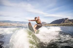a man riding a wave on a surfboard in the water at Spirit Ridge, in The Unbound Collection by Hyatt in Osoyoos