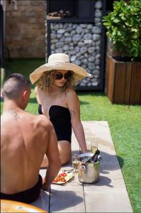 Una mujer con sombrero sentada en una mesa de picnic en Guest house Wishmore, en Banya