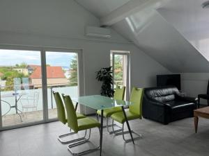 un soggiorno con tavolo in vetro e sedie verdi di Hotel Hippel Krone a Kerzers