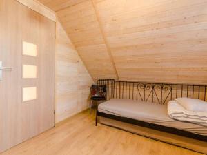 a bed in a room with a wooden wall at Zielona Dolina Rusinowo in Rusinowo