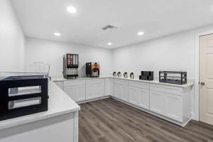 uma cozinha com armários brancos e uma bancada em Travelodge by Wyndham Kissimmee Orlando em Orlando