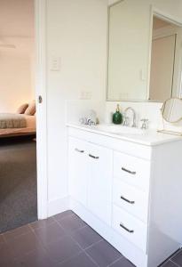 a white bathroom with a sink and a mirror at Cosy hillside studio in Ocean Shores