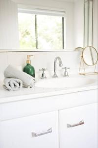 a white bathroom with a sink and a window at Cosy hillside studio in Ocean Shores