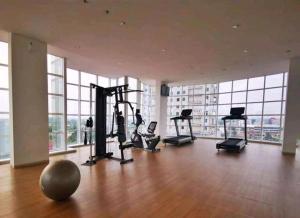 un gimnasio con equipo cardiovascular en una gran sala con ventanas en Ilham Apartemen Batch 1 en Serang