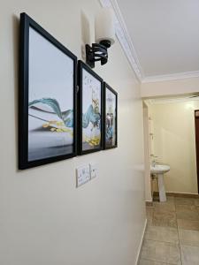 a bathroom with three framed pictures on the wall at Lux Suites Neema court Apartments in Nairobi