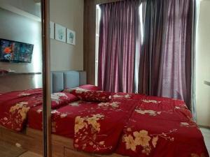 1 dormitorio con cama roja y espejo en Ilham Apartemen Batch 1 en Serang