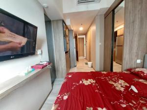 1 dormitorio con cama roja y TV en la pared en Ilham Apartemen Batch 1 en Serang