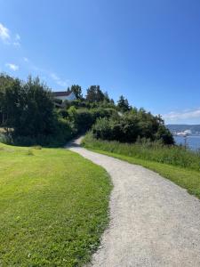 a gravel road next to a field of grass at Leilighet ved Ladestien in Trondheim