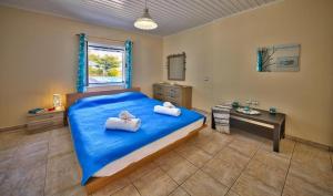 1 dormitorio con 1 cama azul y 2 toallas en Villa Esperanza by Imagine Lefkada, en Lefkada