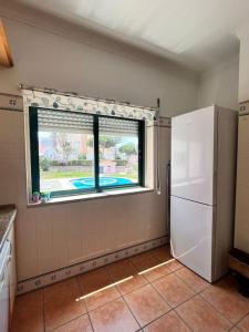 uma cozinha com uma janela e um frigorífico branco em T2 Ocean View House na Ericeira