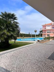 a brick walkway with a palm tree and a swimming pool at T2 Ocean View House in Ericeira