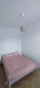 ein Schlafzimmer mit einem rosa Bett mit einer rosa Decke in der Unterkunft Apartament Kopernika in Nowe Miasto Lubawskie