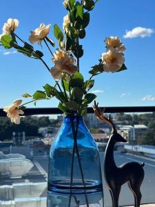 a blue vase with flowers in a window at Fully equipped apartment in Rockdale in Sydney