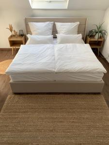 un letto con lenzuola e cuscini bianchi in una camera da letto di Gemütliches & schönes Apartment a Ichenhausen