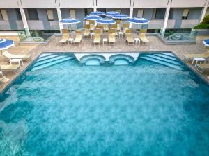 uma piscina com cadeiras e guarda-sóis num hotel em Residence Picalè em Alghero